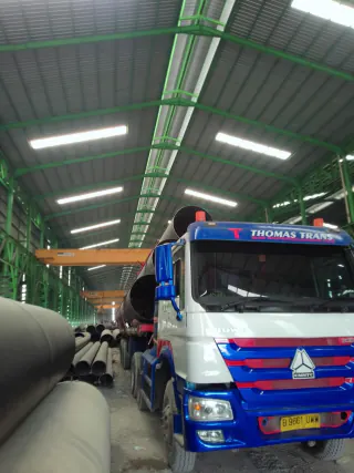Front view of a truck with pipe cargo inside the warehouse