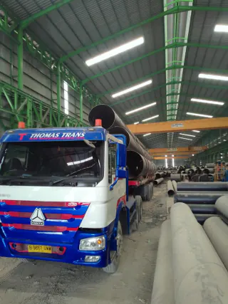 Truck and pipe cargo beside the warehouse storage aisle
