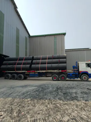Side view of a trailer carrying steel pipes in the warehouse yard